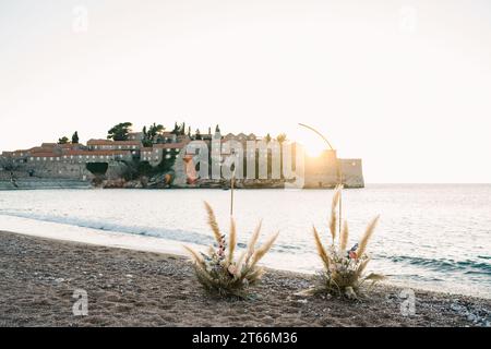Il semi-arco nuziale si erge sulla riva del mare con l'isola di Sveti Stefan sullo sfondo. Montenegro Foto Stock