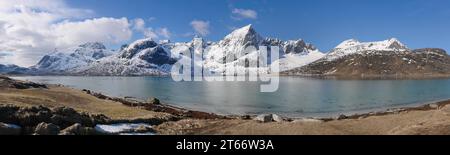 Respirate la splendida cima della montagna Stortind e i laghi della baia Flakstadpollen, Flakstadøy, Lofoten, la natura norvegese, la neve invernale contro il cielo blu, Turquo Foto Stock