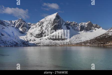 Respirate la splendida cima della montagna Stortind e i laghi della baia Flakstadpollen, Flakstadøy, Lofoten, la natura norvegese, la neve invernale contro il cielo blu, Turquo Foto Stock