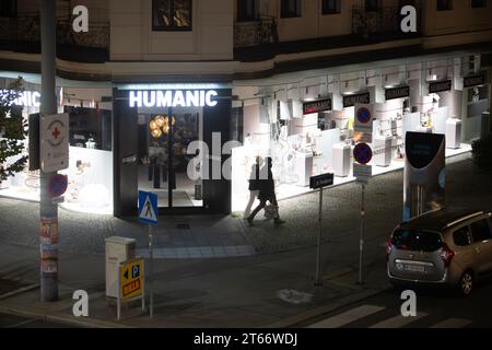 Due uomini camminano di fronte al negozio Humanic, Vienna Austria di notte in inverno, fotografati da un alto edificio Foto Stock