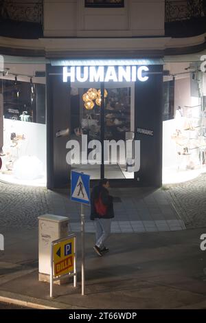 Un uomo cammina di fronte al negozio Humanic, Vienna Austria di notte d'inverno, fotografato da un alto edificio Foto Stock