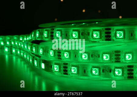 Bobina con rotolo di strisce luminose LED luminose posizionate sul tavolo, colore verde nelle stanze scure Foto Stock
