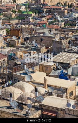 Caotica vista sul tetto di una città del Medio Oriente con piatti satellitari e vasche d'acqua Foto Stock