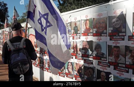 Un uomo detiene la bandiera nazionale israeliana mentre cammina e guarda le foto di ostaggi israeliani rapiti dal gruppo militante palestinese Hamas a Gaza durante una manifestazione tenuta da membri della famiglia degli ostaggi, chiedendo un'azione del governo e il loro rilascio sicuro, fuori dalla Knesset, parlamento israeliano il 6 novembre 2023 a Gerusalemme, Israele. Mentre il governo israeliano promette di eliminare Hamas, i cui attacchi del 7 ottobre hanno lasciato 1.400 morti e oltre 230 rapiti, il destino di quegli ostaggi ha complicato la risposta militare del paese. Foto Stock