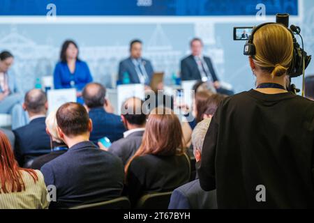 Vista posteriore di una videografa che registra una conferenza globale al forum sull'esportazione Foto Stock