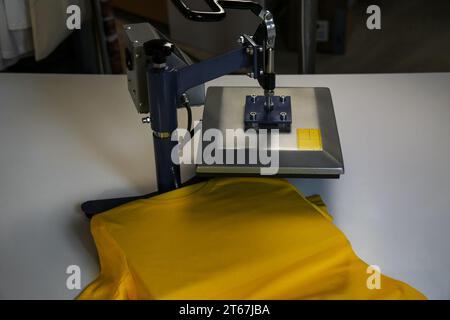 Stampa logo. Pressa a caldo con t-shirt su tavolo bianco Foto Stock