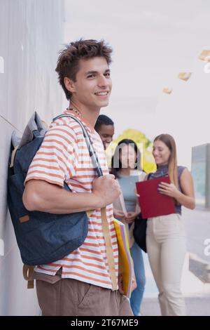 Scatto verticale allievo felice nel campus sorridendo davanti alla telecamera all'aperto. Foto Stock