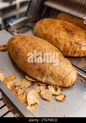 Macchina per affettare il pane. Pane affettato sulla linea di produzione di prodotti alimentari e da forno. Foto Stock