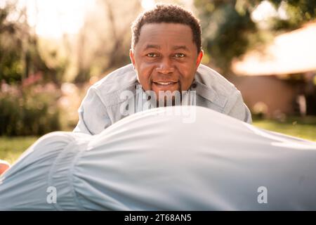 Una donna latina incinta e una coppia di uomini africani in un lussureggiante parco illuminato dal sole Foto Stock