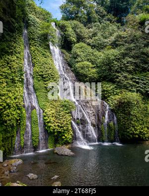 Una vista panoramica di una cascata che scende tra le rocce in una giungla verde Foto Stock