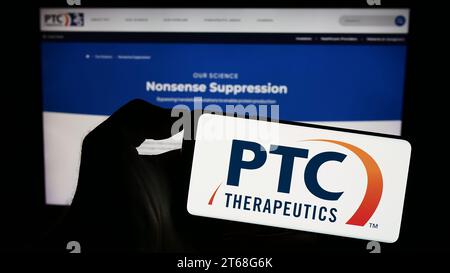 Persona che possiede il cellulare con il logo della società farmaceutica statunitense PTC Therapeutics Inc. Davanti alla pagina Web aziendale. Concentrarsi sul display del telefono. Foto Stock