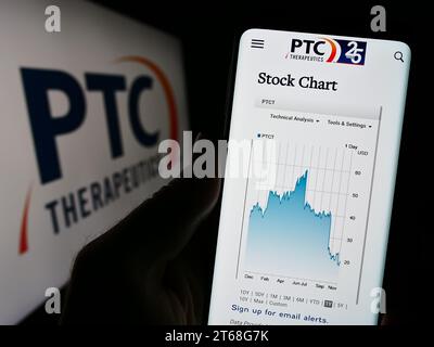 Persona che possiede uno smartphone con la pagina Web dell'azienda farmaceutica statunitense PTC Therapeutics Inc. Davanti al logo. Concentrarsi sul centro del display del telefono. Foto Stock