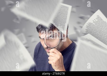 Un uomo caucasico con una camicia blu tiene una lente d'ingrandimento fino a una pila di carte, che sembra studiare o analizzare il contenuto Foto Stock