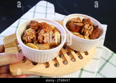 Tenendo a mano una tavola di deliziose ciotole di budino di pane al banana appena sfornate Foto Stock