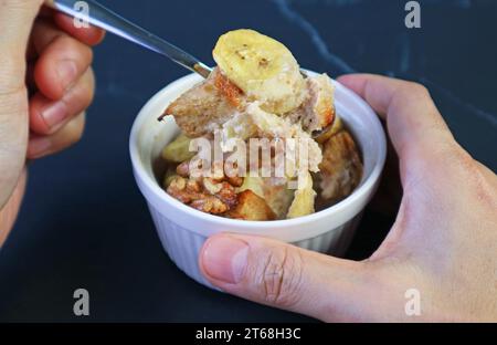 Gusta l'appetitoso budino di pane di noce alla banana da una ciotola in ceramica Foto Stock