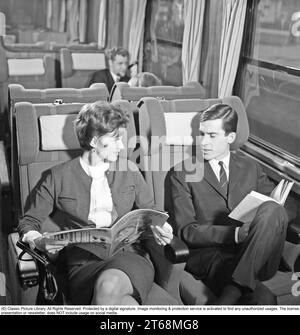 Viaggi in treno negli anni '1960 Una coppia su un treno, seduto comodamente in carrozza leggendo una rivista e un libro. Svezia 1960s Kristoffersson rif DD118-11 Foto Stock
