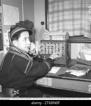 La telefonia negli anni '1940 Un uomo con un abbigliamento tradizionale sami a un centralino telefonico. Collega le chiamate in entrata e in uscita alla persona giusta utilizzando i cavi per i rispettivi telefoni in un centralino telefonico. Svezia 1943 Kristoffersson rif. D127-4 Foto Stock