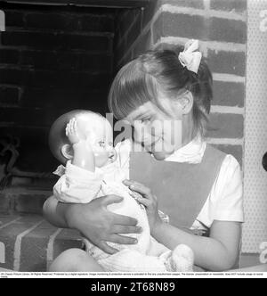 Una ragazza con una bambola negli anni '1950 Una bambina sta giocando con la sua bambola. Svezia 1956. Kristoffersson rif. BS39-11 Foto Stock