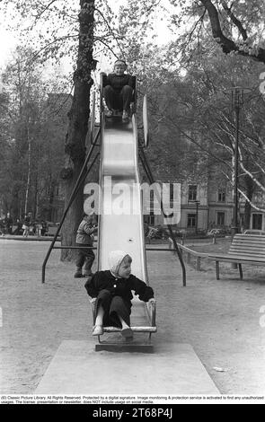 Parco giochi negli anni '1950 I bambini vengono visti scendere da uno scivolo in un parco a Stoccolma Svezia 1954. Kristoffersson rif. 1-38 Foto Stock