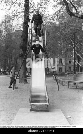 Parco giochi negli anni '1950 I bambini vengono visti scendere da uno scivolo in un parco a Stoccolma Svezia 1954. Kristoffersson rif. 1-38 Foto Stock