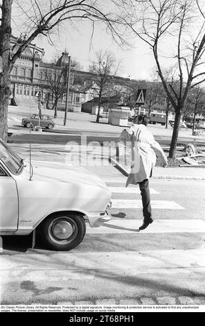 Negli anni '1960 Un momento in cui un uomo cammina su un attraversamento pedonale ma un'auto non l'ha notato e continua a guidare. L'uomo si allontana dalla macchina per evitare di essere colpito da essa. Svezia 1968. Kristoffersson rif. 3-57 Foto Stock