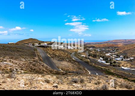 Una vista panoramica di una strada di campagna che conduce a pittoresche colline ondulate sullo sfondo, con una vasta spiaggia di sabbia in primo piano Foto Stock