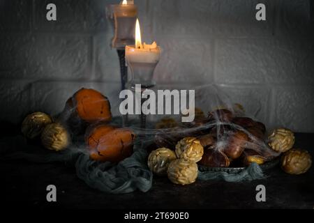Uno scatto ravvicinato di una candela luminosa e una selezione di frutta colorata su un tavolo di legno Foto Stock