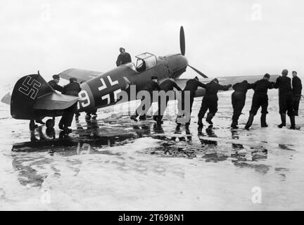 Un aereo da caccia Messerschmitt me BF 109 viene spinto sulla pista di un aeroporto tedesco fuggito dall'equipaggio di terra. Indossa una livrea nera di un'unità post-caccia nel Reichsverteidigung. Foto: Stöcker. [traduzione automatica] Foto Stock