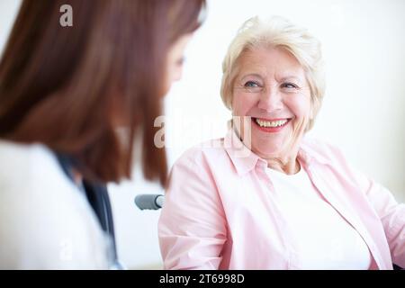 Rapporti amichevoli con il medico e il paziente - Senior Health. Una donna anziana in sedia a rotelle sorride alla sua amichevole infermiera. Foto Stock