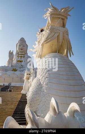 I draghi cinesi allineano i gradini fino alla statua di Guan Yin (Dea della Misericordia) al tempio Wat Huay Pla Kang nella provincia di Chiang Rai nella Thailandia settentrionale Foto Stock
