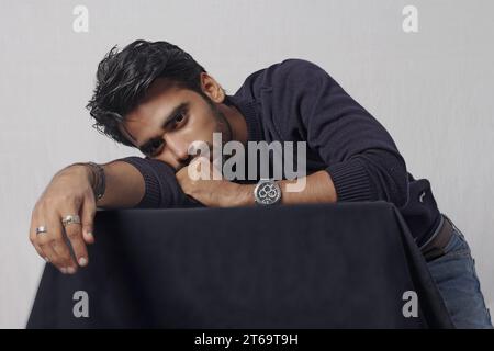 Giovane seduto su una sedia e guardando la macchina fotografica. foto di alta qualità Foto Stock