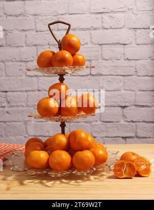 Piatto di cristallo antico con arance piccole. Dessert Display con parete di mattoni sullo sfondo Foto Stock