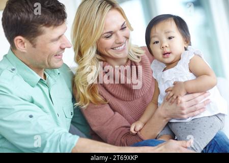 Scopa la nostra grande ragazza. Una coppia felice che passa del tempo con la loro bella figlia adottiva mentre è a casa. Foto Stock