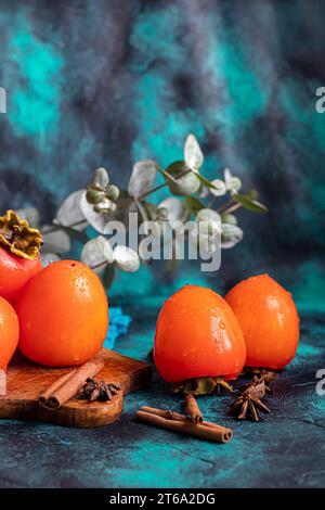 Cachi su sfondo scuro. Frutta fresca matura su un piatto blu e in scatola. Mangiare sano. Foto Stock