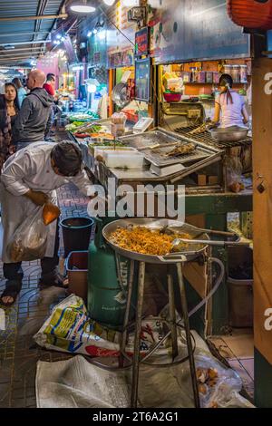 Venditore di strada thailandese che prepara piatti di pesce al mercato notturno nel centro di Chiang Rai, Thailandia Foto Stock