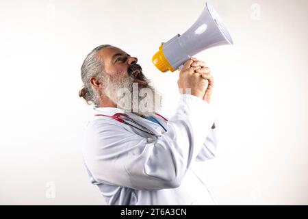 Un uomo maturo e barbuto sta con sicurezza con un megafono alzato alle labbra, pronto a rivolgersi a una folla Foto Stock