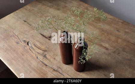 Composizione artistica minimalista. Frammenti di un'antica casa di campagna all'interno - pareti intonacate illuminate, un antico tavolo in legno, bottiglie smaltate in argilla Foto Stock