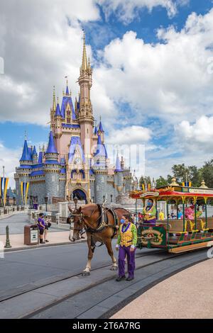 Il personaggio dei maialini cavalca un tram trainato da cavalli oltre il castello di Cenerentola, seguito da Tigro e Winnie the Pooh sulla Main Street nel Magic Kindom Foto Stock