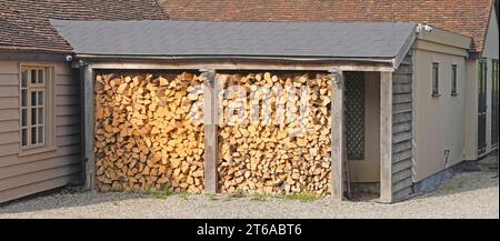 Struttura da povera a riparata e protezione del tetto inclinata per tagliare i tronchi di legno immagazzinati all'esterno carburante invernale caminetto aperto al coperto nell'Essex Inghilterra Regno Unito Foto Stock