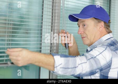 addetto alla costruzione che mette il nastro di schiuma sigillante sulla finestra in casa Foto Stock