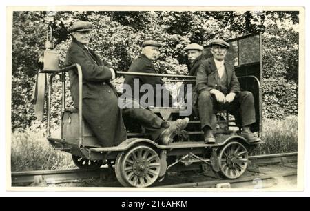 Cartolina originale del tardo Edoardiano o dei primi anni '1920 con 4 addetti alla manutenzione che indossano berretti piatti su un carrello per la manutenzione dei binari ferroviari/carrozza dell'equipaggio, jigger/quad/trolley, auto per ispezione, o drenaggio - si trattava di piccole automotrici ferroviarie utilizzate in passato in tutto il mondo da ispettori di binari e personale di lavoro per spostarsi rapidamente da e verso i siti di lavoro. Circa 1927, Regno Unito Foto Stock