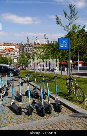 Scooter elettrici parcheggiati presso il punto di condivisione, la chiesa di Igreja dos Congregados e la torre del municipio in lontananza, Ribeira, Porto/Porto, Portogallo Foto Stock