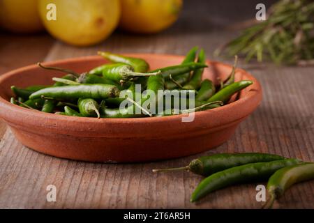 Piatto con peperoni verdi sciolti con alcuni limoni ed erbe sullo sfondo. Foto Stock