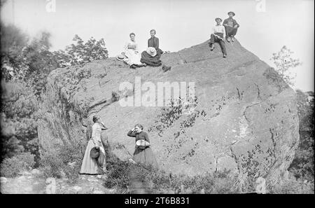 Antichità risalente al 1885 circa fotografia, gruppo di uomini e donne di mezza età all'aperto, arrampicata su una grande roccia; un uomo tiene una "tasca" o un "fucile da bicicletta". Posizione esatta sconosciuta, probabilmente Maine, USA. FONTE: ORIGINALE 5X8 VETRO NEGATIVO Foto Stock