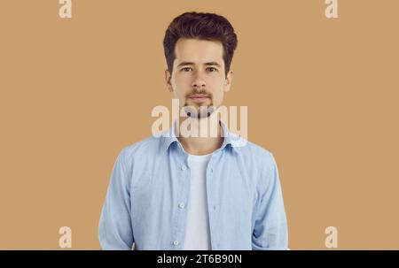 Ritratto di un giovane sorridente con barba e baffi ben rasati, vestito con T-shirt bianca e camicia blu, che guarda con sicurezza direttamente nel Foto Stock
