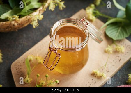 Miele in un vaso di vetro con fiori e foglie di lino freschi Foto Stock