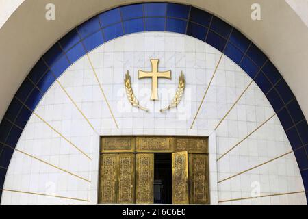 020 porta in marmo bianco incorniciata da un arco di vetro blu, croce dorata e porte, Cattedrale Ortodossa della Resurrezione. Tirana-Albania. Foto Stock