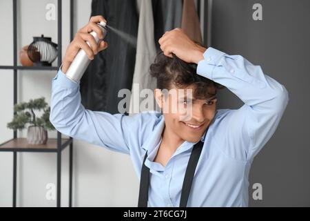 Bel giovane che applica spray sui capelli ricci in corridoio Foto Stock