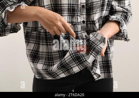 Donna che mostra macchie di salsa sulla camicia su sfondo bianco, primo piano Foto Stock