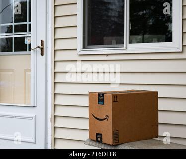 Una scatola di consegna Amazon prime lasciata su una panchina vicino a una porta Foto Stock